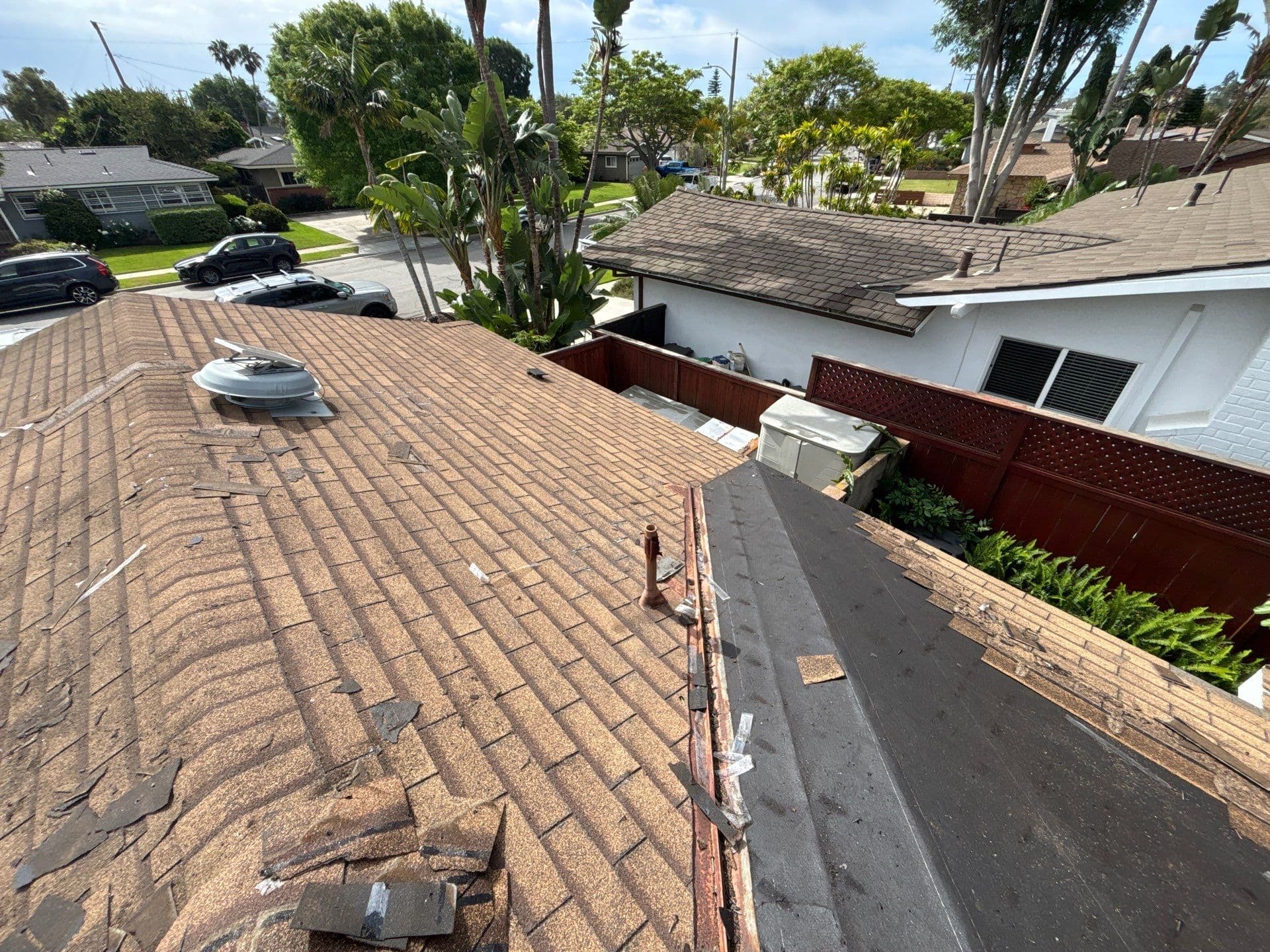 Storm-damaged roof with torn shingles and debris before repair